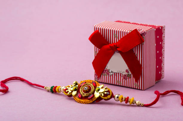 Raakhi and a gift for the sister given by brother on the occasion of Raksha Bandhan. Indian festival Raksha Bandhan background with an elegant Rakhi. Raakhi and a gift for the sister given by brother on the occasion of Raksha Bandhan. Indian festival Raksha Bandhan background with an elegant Rakhi. rakhi stock pictures, royalty-free photos & images