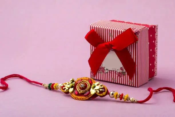 Raakhi and a gift for the sister given by brother on the occasion of Raksha Bandhan. Indian festival Raksha Bandhan background with an elegant Rakhi.