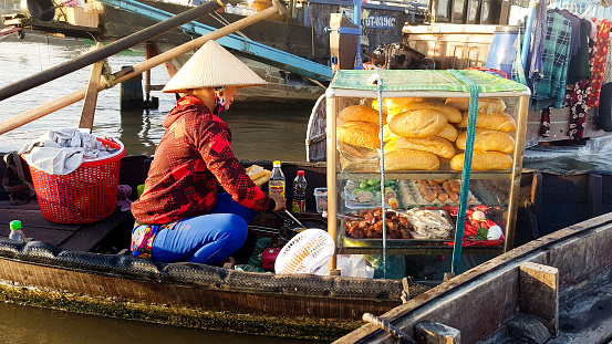 A boat food vendor selling banh mi (baguette) at the traditional Vietnamese floating market called Cai Rang in Can tho, Vietnam