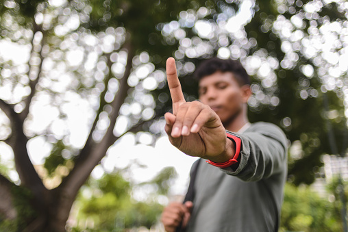 Teenage student holding up index finger, in a gesture that means the number one