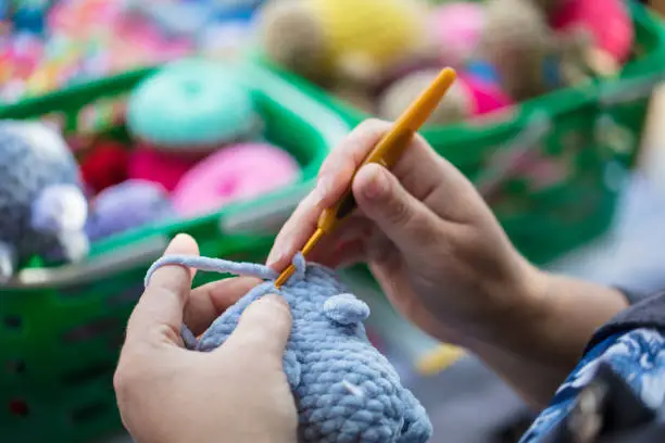 Hands of a needlewoman crochet. Female fingers knit a toy. Handmade craft.