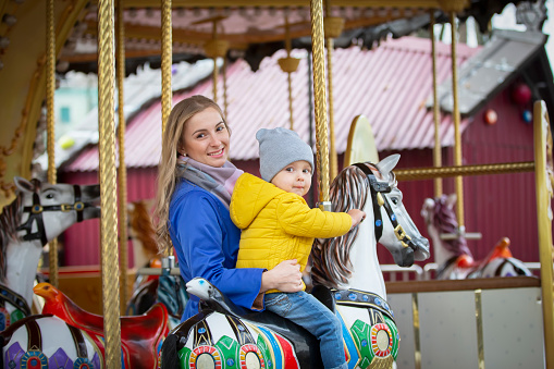 Mom with a cheerful baby on a carousel.Little son with mom in the park.