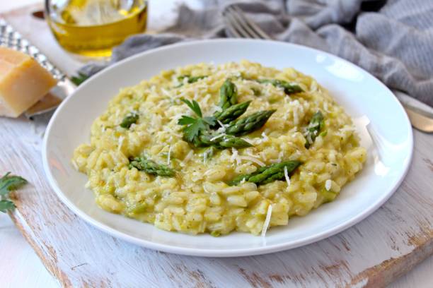 Italian risotto with spring asparagus and parmesan cheese in plate on light background. stock photo