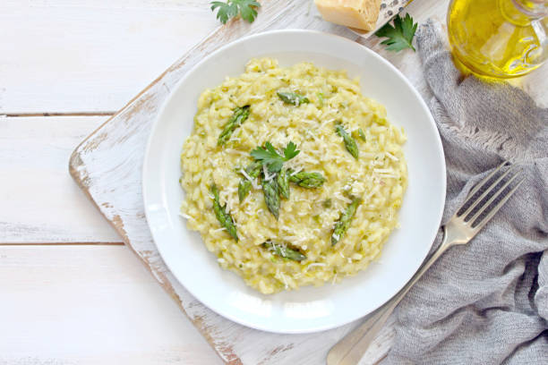 istock Italian risotto with spring asparagus and parmesan cheese in plate on light background. 1197141371