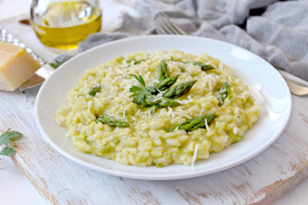 istock Italian risotto with spring asparagus and parmesan cheese in plate on light background. 1197141430