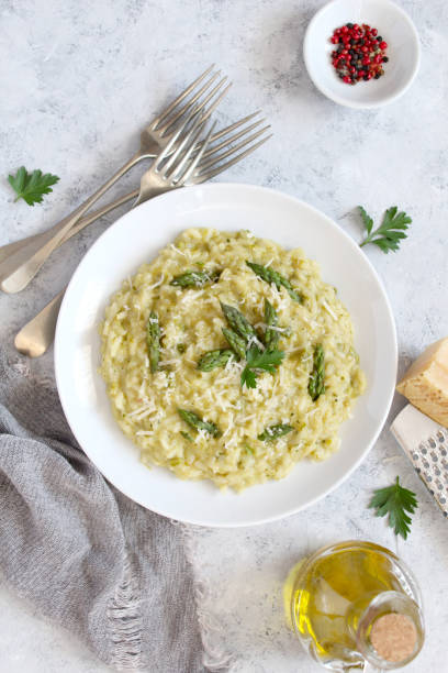 istock Italian risotto with spring asparagus and parmesan cheese in plate on light background. 1197141551