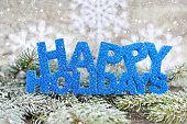 Inscription of happy holidays with spruce branches with frost