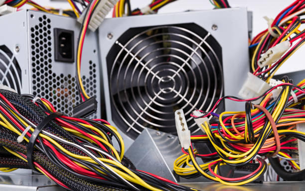 Discarded electrical device with fan in square metal box and tangle of insulated wires. Electronic waste sorting, recycling or disposal. Garbage dump. Eco