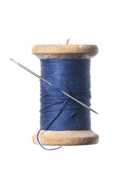 Old wooden spool of thread and a needle. Sewing