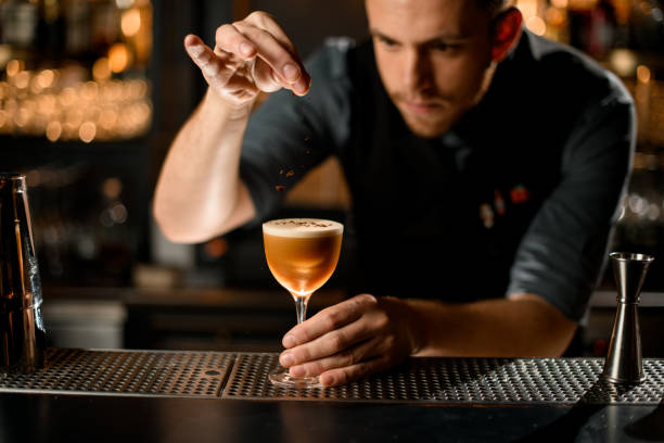 istock Male bartender serving the brown alcoholic drink sprinkling on it with spices 1197154250