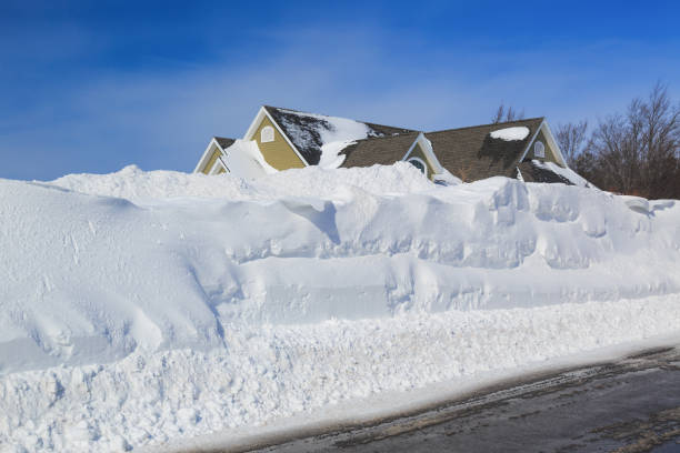 High snowbanks on the sides of a plowed road in an urban neighborhood.
