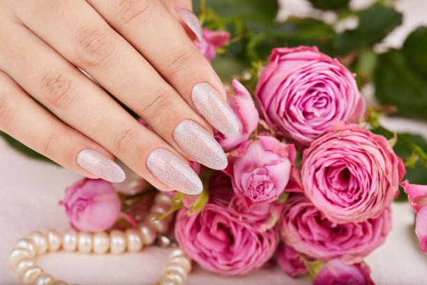 istock Hand with long manicured nails colored with nail polish with silver glitter 1197154869