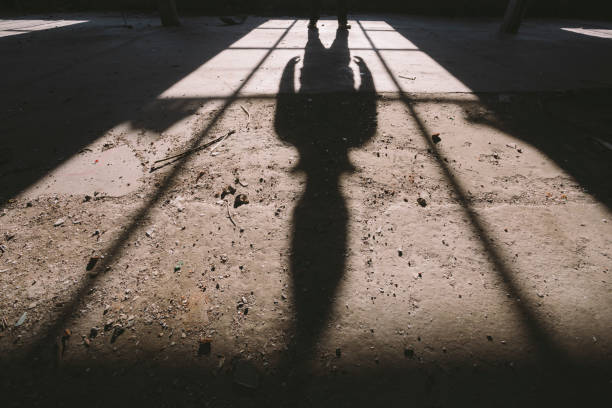 istock Adult man standing inside some large, dark, spooky,abandoned building illuminated with sunlight through window 1197158446