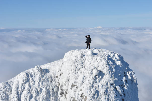 istock Lonely mountaineer get rest on snowy mountain high above the clouds 1197159611