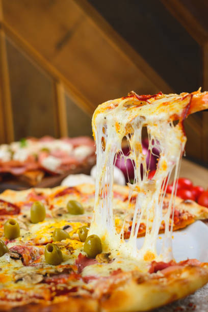 istock Hot capricciosa pizza slice with melted cheese stretching from the white plate 1197160785