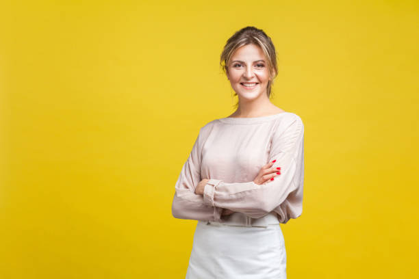 retrato de una hermosa mujer positiva con pelo rubio en blusa beige casual, aislada sobre fondo amarillo - blouse fotografías e imágenes de stock