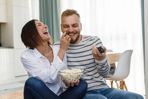 istock Young couple eating popcorn watching TV having fun 1197161273