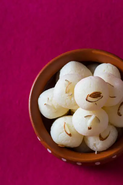 Indian Sweet or Dessert - Rasgulla, Famous Bengali sweet in clay bowl on a pink background.