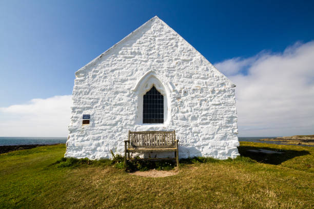 Whitewashed front of church in the sea Eglwys Cwyfan. Aberffraw, Anglesey, Wales, United Kingdom, landscape.