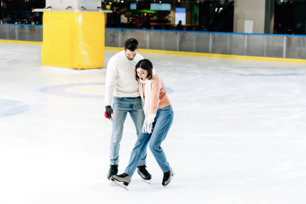 istock young couple skating together while woman falling on rink 1197172466