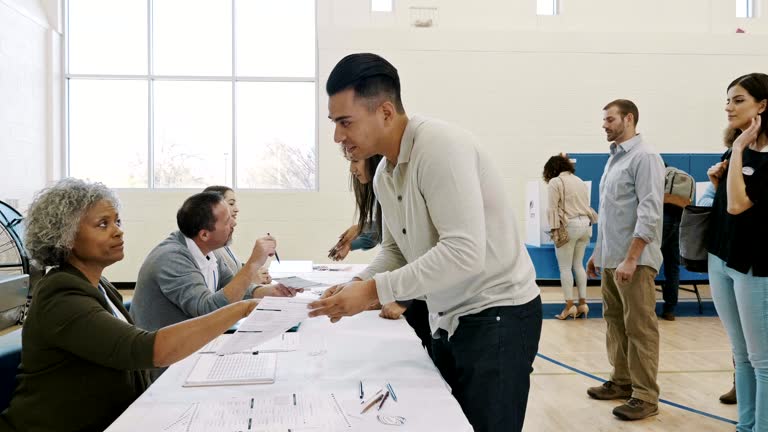 Female polling place volunteer explains ballot to male voter