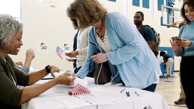 Female polling place volunteer assists female voter