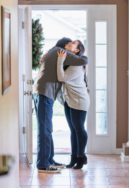 starszy latynoski mężczyzna otwiera drzwi, wita gościa - home interior arrival father family zdjęcia i obrazy z banku zdjęć