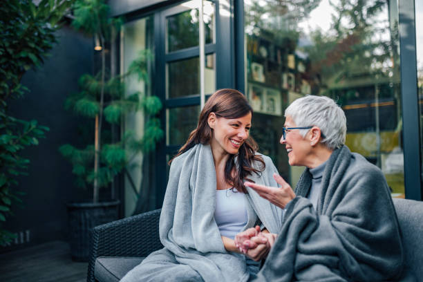 concepto de reunión familiar. dos mujeres de diferentes edades hablando en el patio de la casa moderna. - hijo adulto fotografías e imágenes de stock