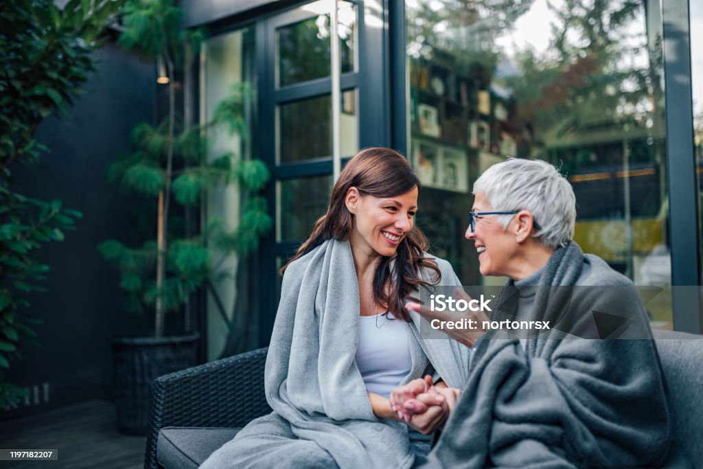 Family gathering concept. Two women of different age talking on the patio of modern house. Family Stock Photo
