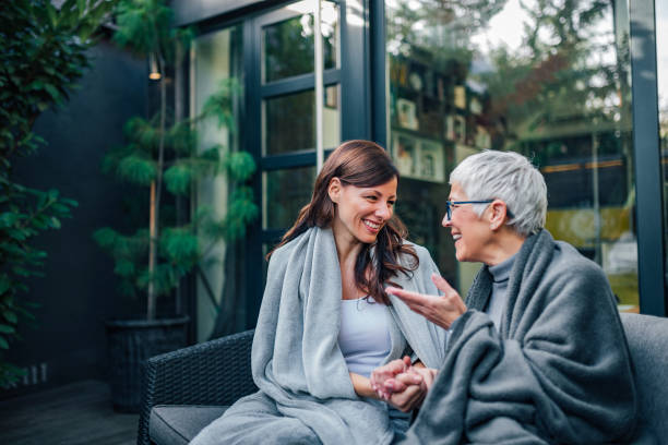 Family gathering concept. Two women of different age talking on the patio of modern house. Family gathering concept. Two women of different age talking on the patio of modern house. adult offspring stock pictures, royalty-free photos & images