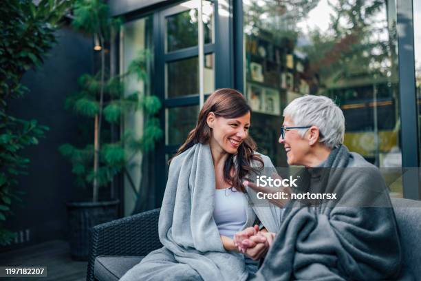Family Gathering Concept Two Women Of Different Age Talking On The Patio Of Modern House Stock Photo - Download Image Now