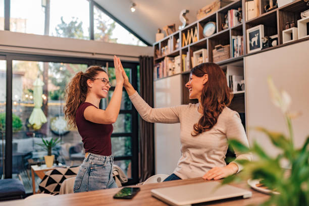 istock Two cheerful women high five at cozy modern house. 1197182242