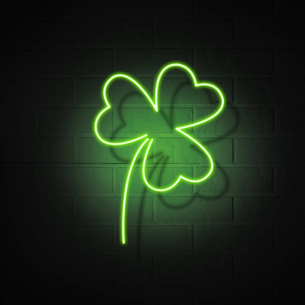 Neon signboard in the shape of a clover trefoil on a brick wall background. The symbol of the holiday St. Patrick's Day. stock photo