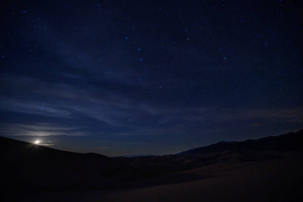 księżyc ustawia się poniżej wydm i pola gwiazd - night sky zdjęcia i obrazy z banku zdjęć