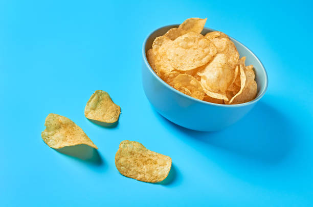 istock Full ceramic bowl of potato chips on blue background. Close-up 1197184620