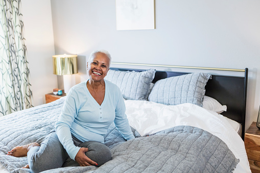 A woman in jeans smiling on her bed.Portrait of a woman.