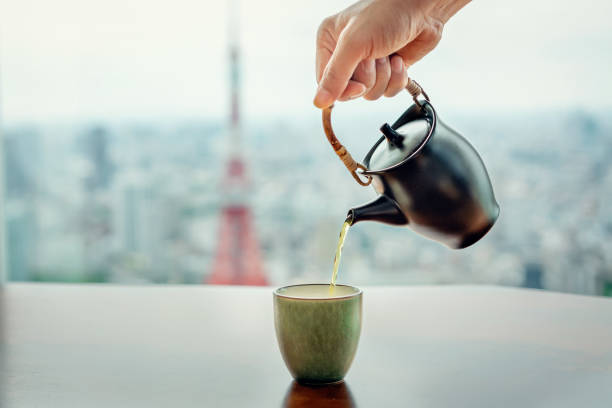 gießen von grünem tee auf der aussicht auf tokyo tower - japanese tea cup stock-fotos und bilder