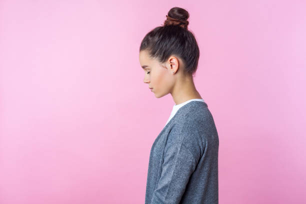 Side view of sleepy brunette teenage girl standing dreaming or imagining with closed eyes. isolated on pink background Side view of sleepy brunette teenage girl with bun hairstyle in casual clothes standing dreaming or imagining with closed eyes, calm concentrated face. indoor studio shot isolated on pink background sad 15 years old girl stock pictures, royalty-free photos & images