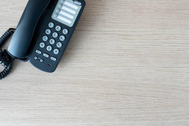 The old black phone on the business office desk in the wood be used for contact Connect, above on table top view Employees are waiting to hear from customers and other departments. el viejo teléfono negro en el escritorio de la oficina de negocios en la madera se utiliza para el contacto conectar, arriba en la vista superior de la mesa los empleados están esperando para escuchar de los clientes y otros departamentos.