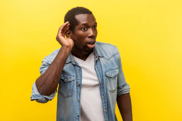 portrait of attentive surprised man listening carefully to rumors. indoor studio shot isolated on yellow background - spy secrecy top secret mystery imagens e fotografias de stock