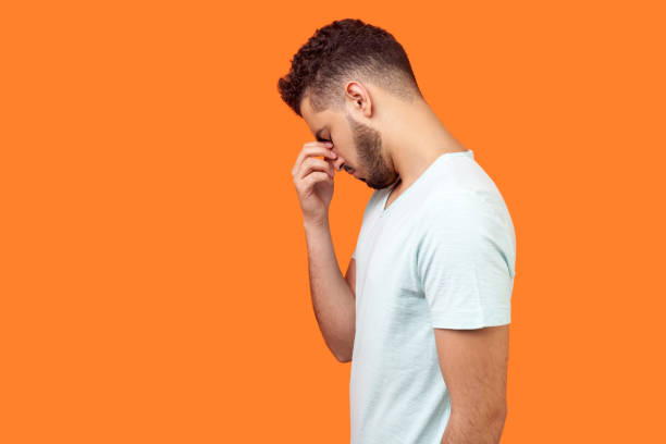 istock Side view of depressed brunette man hiding face in hand, looking desperate. studio shot isolated on orange background 1197197343