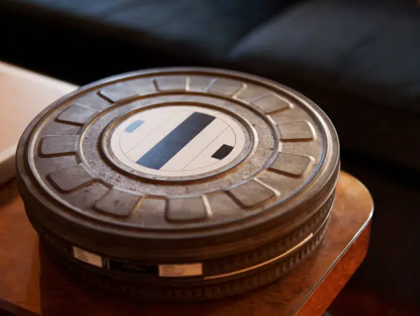 Close-up of old metal movie film reel canister on a wooden table
