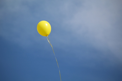 Blue sky with wispy white clouds and a yellow balloon