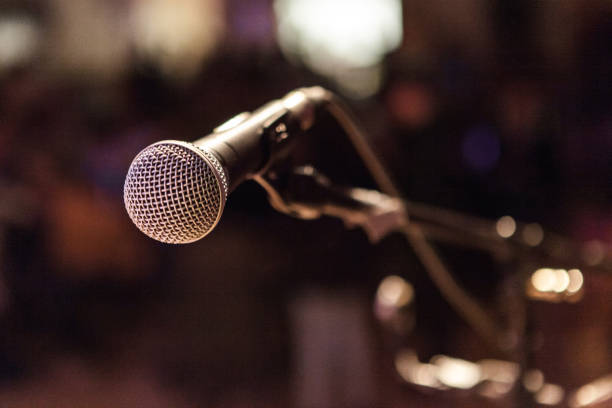 istock Vocal microphone pictured on a stage with a blurry background with bokeh 1197205264