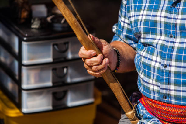 istock Native man in blue shirt is holding a primitive tool used to light a campfire 1197210800
