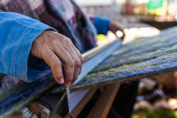 istock Man is weaving very fancy multi colored wool using a wooden loom 1197210930