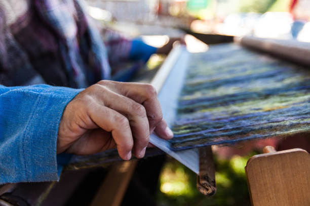 istock Man is weaving very fancy multi colored wool using a wooden loom 1197211571