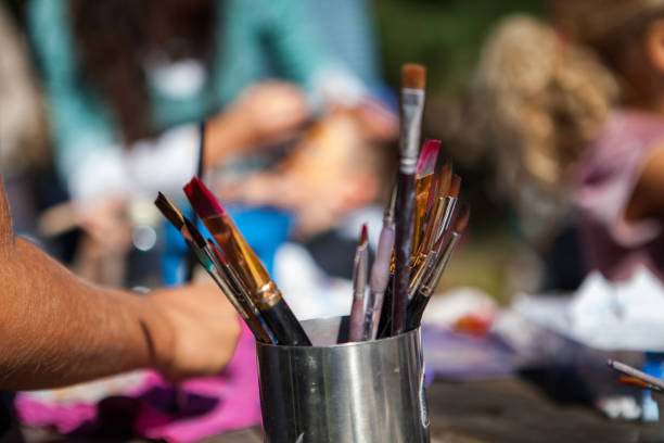 istock Metal container full of paintbrushes while kids are sitting outside 1197211609