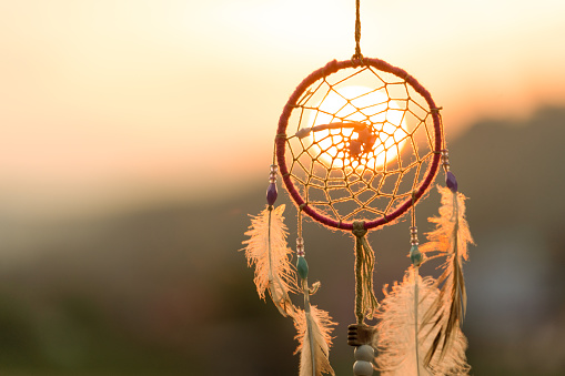 Dream cathcher amulet with sunset in background.Dream catcher is a handmade willow hoop woven to a web or literally  includes such features as feathers and beads