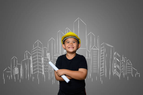 istock A boy wearing a yellow engineer hat and a house plan on a blackboard 1197220527